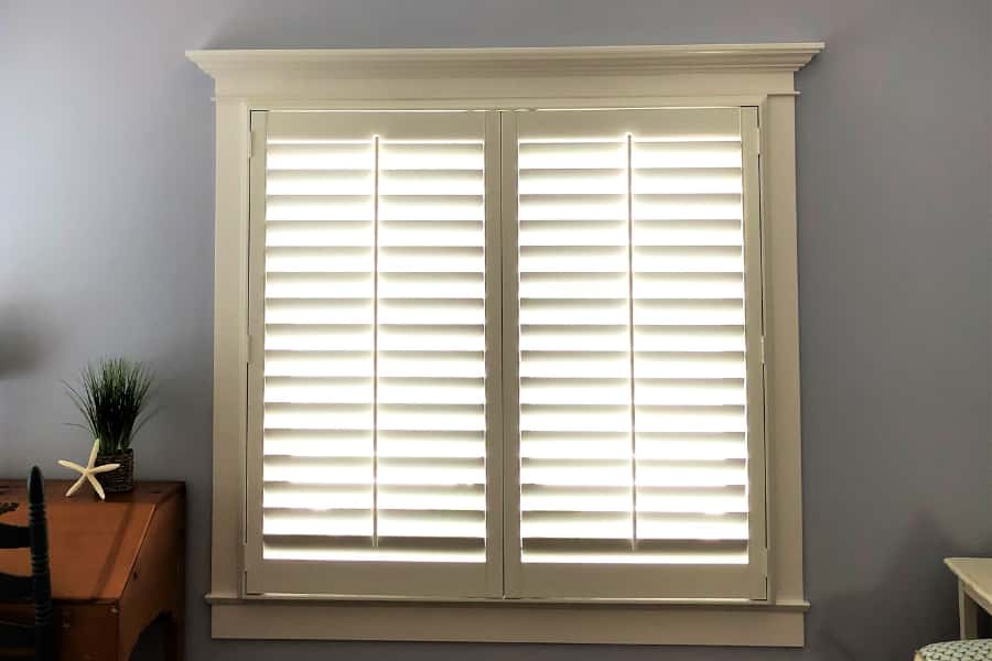 Wood and faux-wood interior shutters display quality and decorative detail. White Polywood shutters in a living room